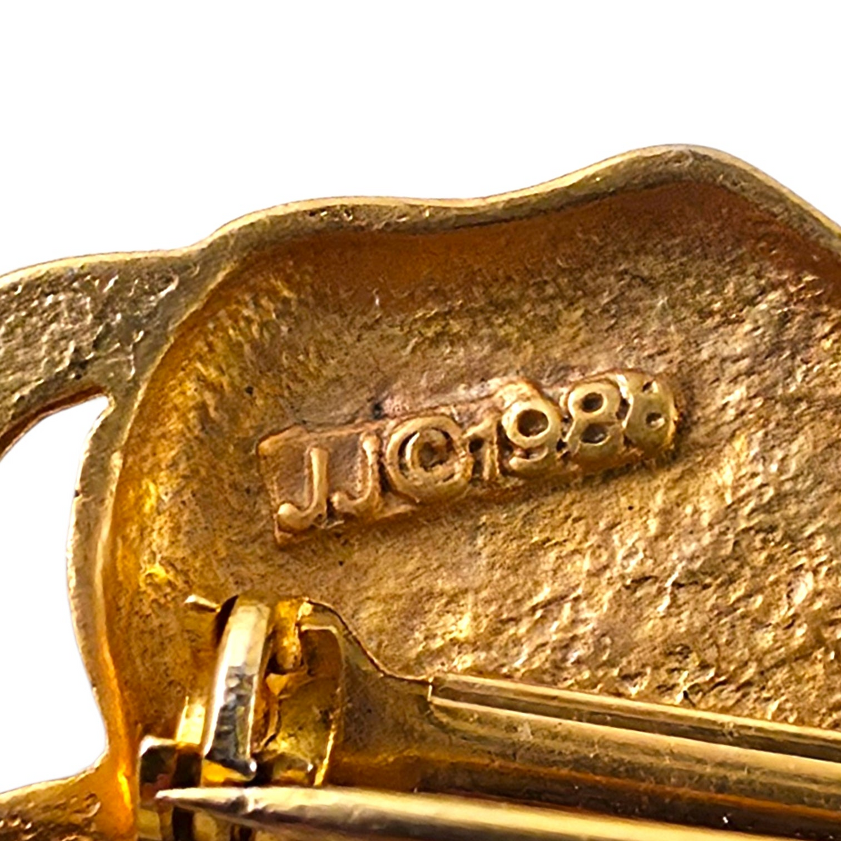 FuzzBeez vintage 1988 JJ signed matte gold-tone running cow brooch back view showing maker mark and pin closure